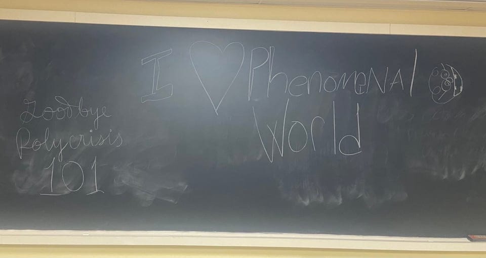 Photo of a large classroom size blackboard saying: "Goodbye Polycrisis 101" and "I (heart) Phenomenal World"